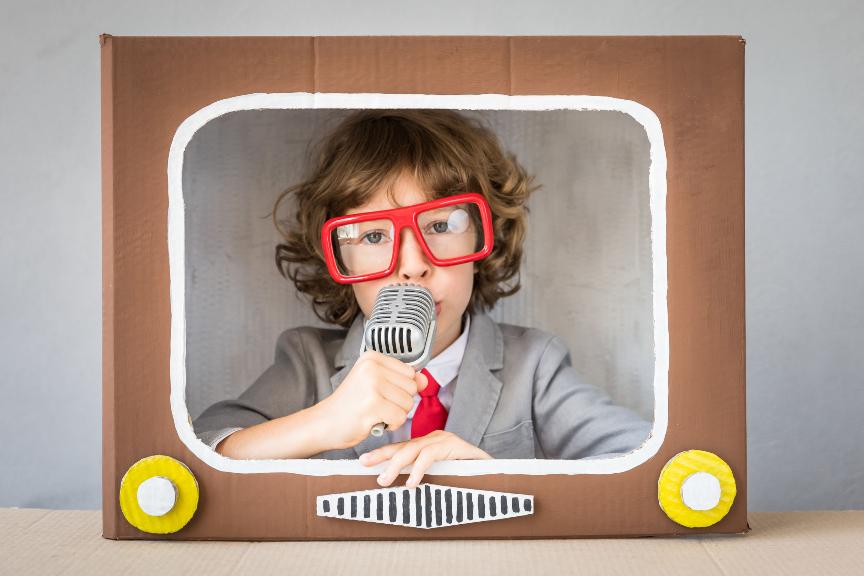 Child playing with cardboard box TV. Kid having fun at home. Communication concept