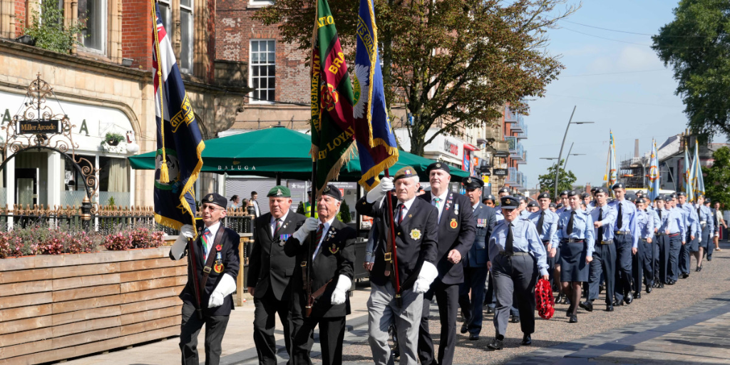 Army representatives marching through Preston carrying flags