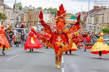 A lady dressed in a large, vibrant, red outfit in the carnival procession