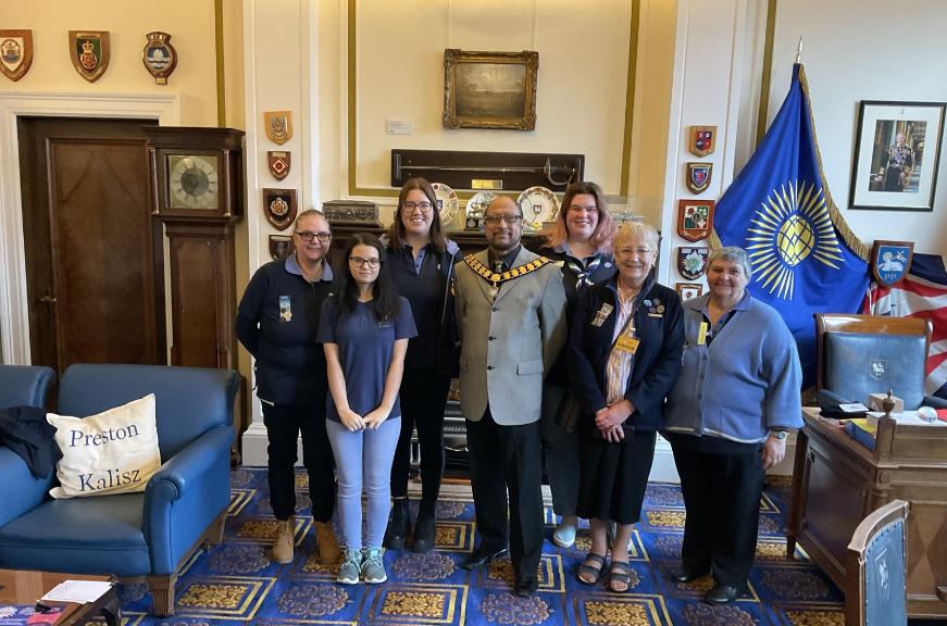 The Major of Preston stood in his parlor with some girl guides, celebrating 100 years.