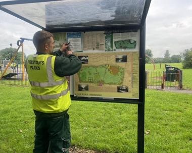 Park Ranger putting leaflet on notice board