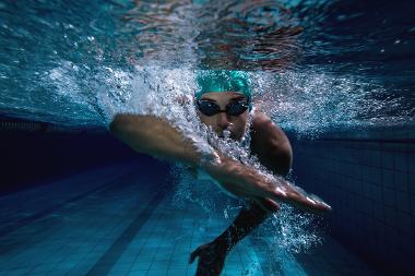 Beneath the surface, a swimmer glides through the water, propelled by determination and skill. With every stroke, they cut through the shimmering blue, embodying the spirit of competition and grace in the aquatic arena.